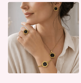 Model in a cream shirt wearing a matching gold hexagonal black-dial jewelry set — earrings, ring, necklace, and bracelet.
